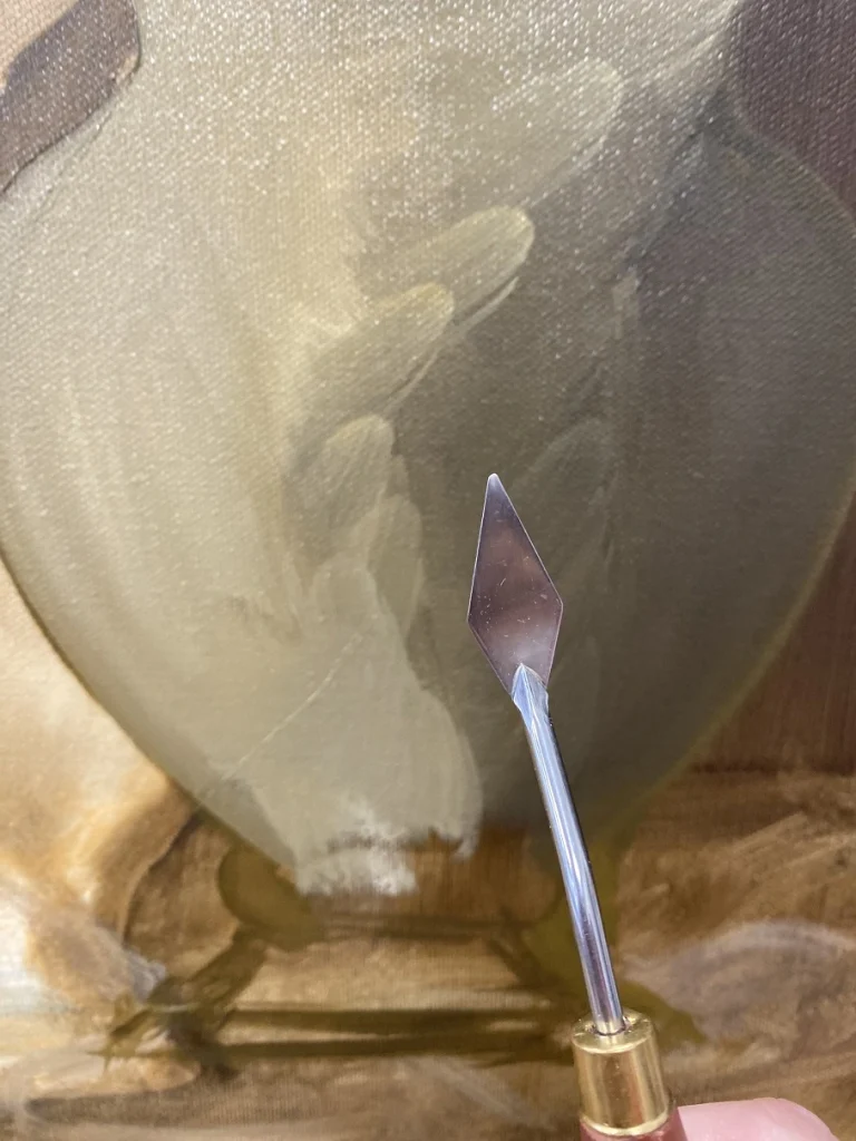 Couteau à peindre présenté devant une toile à corriger en peinture à l’huile